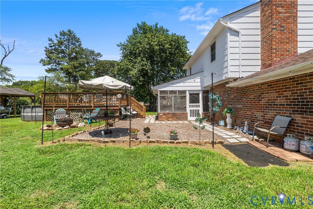 Expansive backyard featuring a multi-level wood deck, a screened porch, a brick exterior, and a stone paver walkway