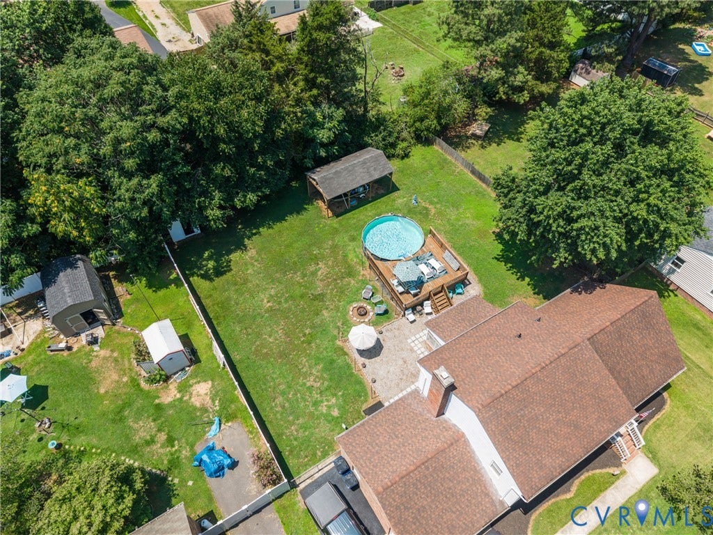 Spacious backyard featuring an above-ground pool with an attached deck, a stone patio, and mature trees