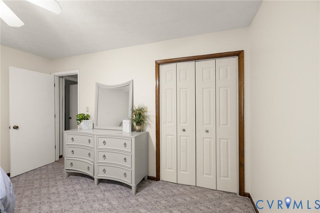 Bi-fold closet doors with wood trim and wall-to-wall carpeting