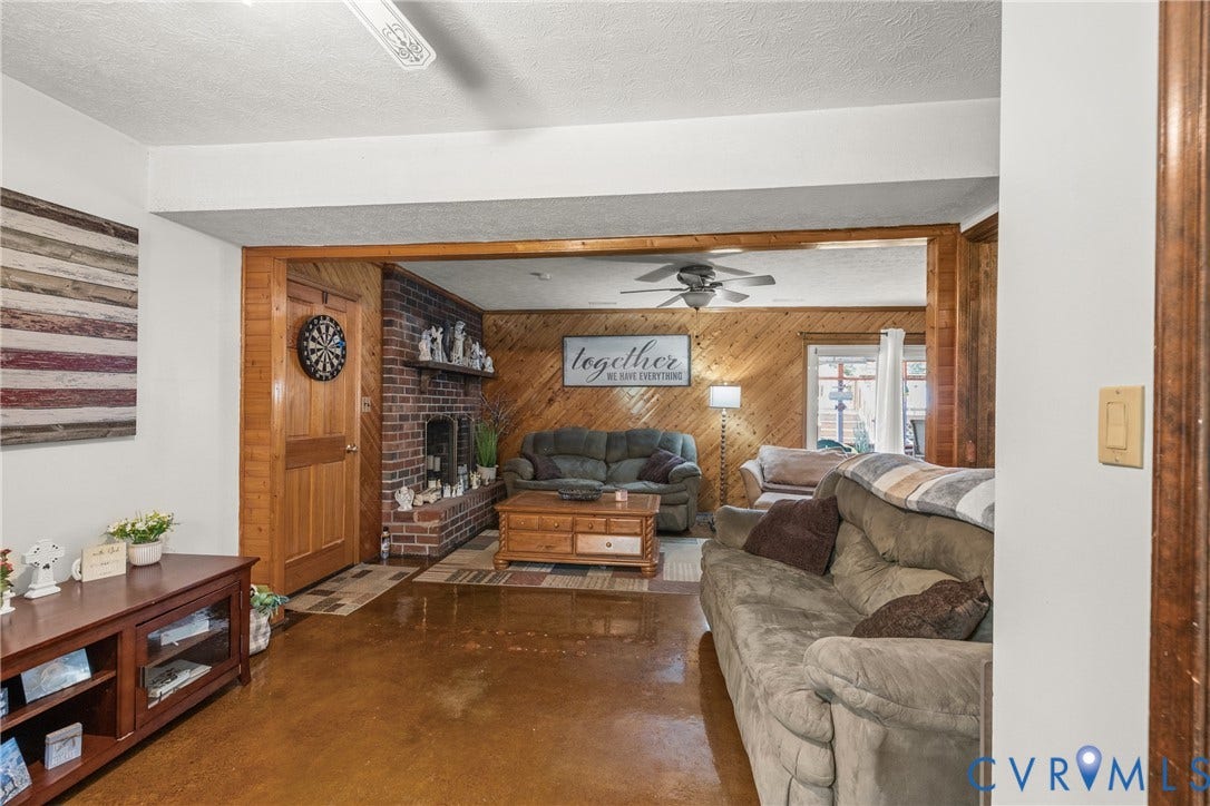 Spacious living area featuring wood-finish flooring, a brick fireplace, and wood paneling