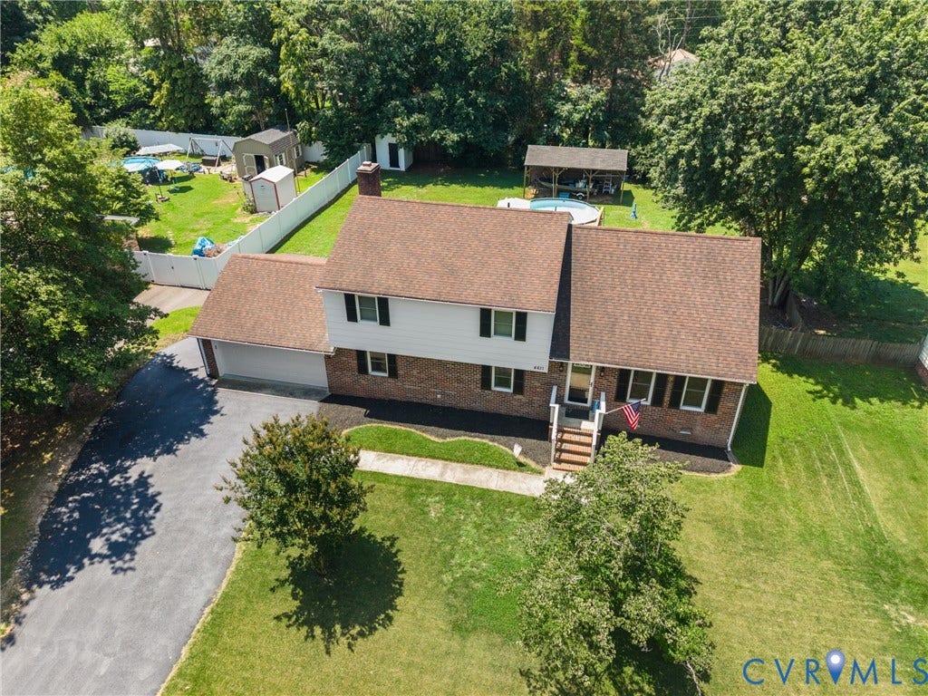 Split-level residence featuring a brick and siding exterior, attached garage, and a spacious backyard with an above-ground pool