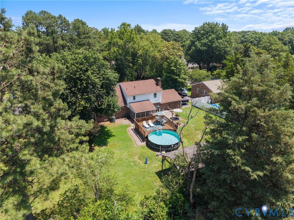 Expansive backyard featuring a manicured lawn, a raised wood deck, and a round above-ground pool