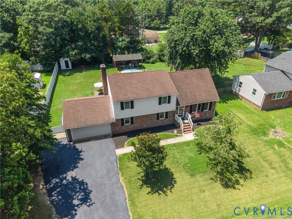 Traditional two-story residence featuring a brick and siding exterior, an attached two-car garage, an expansive paved driveway, and a spacious fenced backyard with mature trees