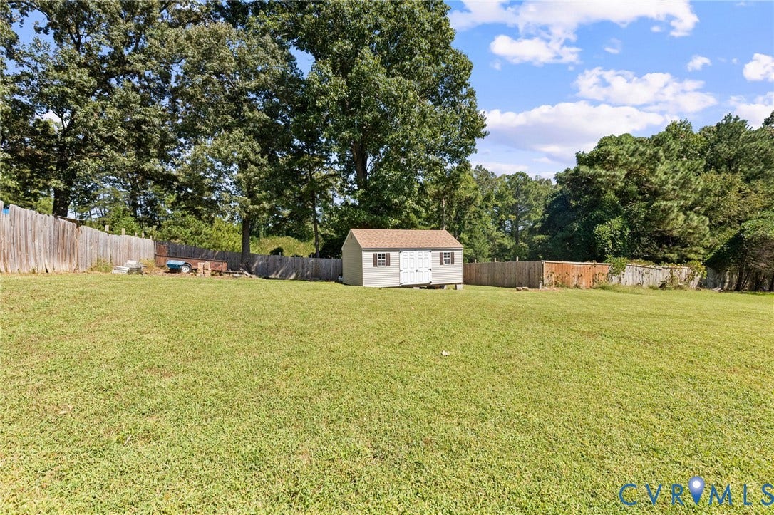 14119 Kentwood Forest Drive, Kentwood Forest, Chester, VA 23831 Expansive grassy yard with a wooden storage shed, bordered by a wood privacy fence and mature trees