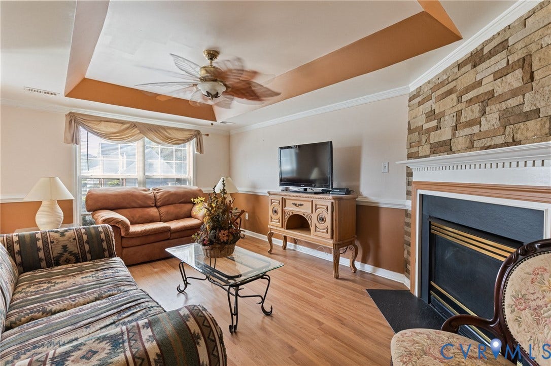 14119 Kentwood Forest Drive, Kentwood Forest, Chester, VA 23831 Tray ceiling with a ceiling fan, wood-finish flooring, and a fireplace featuring a stone surround