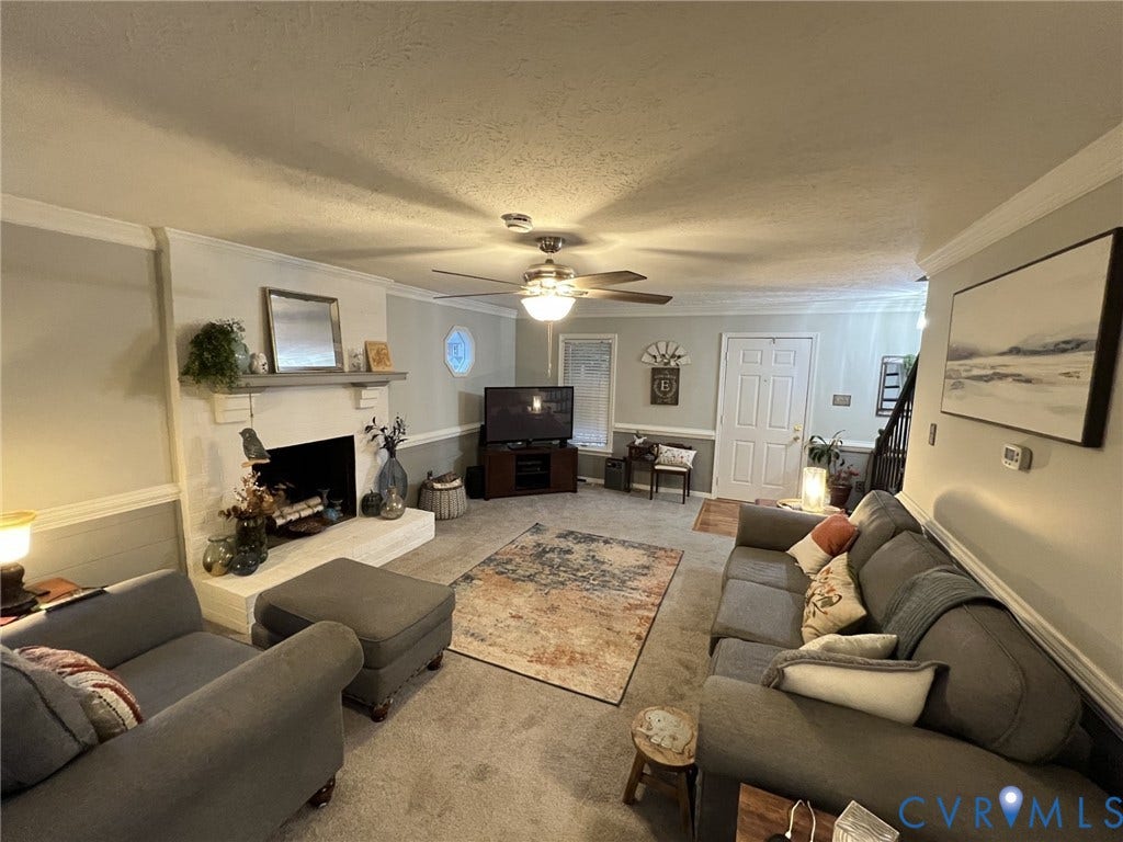 8336 Devils Den Lane, Mechanicsville, VA 23111 Carpeted living area featuring a fireplace with a mantel, crown molding, and a ceiling fan