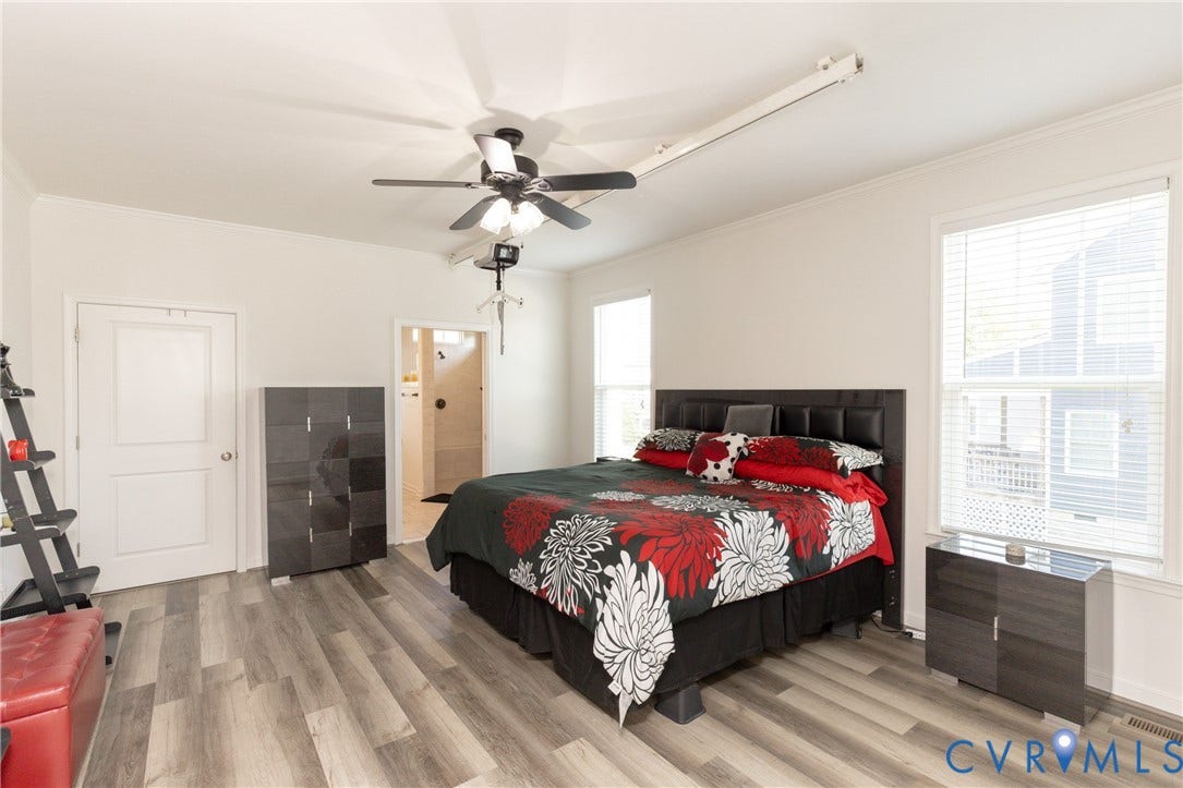 Wood-finish flooring throughout, bright white walls, and a ceiling fan with integrated lighting