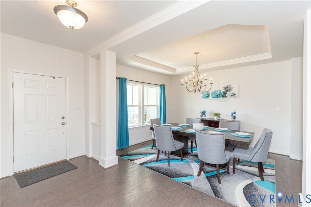 Tray ceiling with crown molding, chandelier lighting, and a paneled entry door