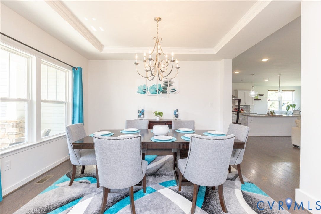 Dining area featuring a tray ceiling, chandelier, large windows, and wood-finish flooring