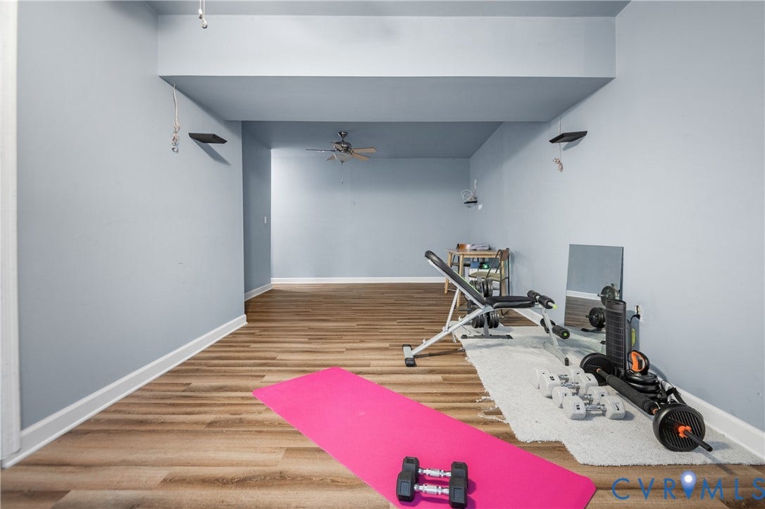 Spacious interior with wood-finish flooring, light-toned walls, and a ceiling fan