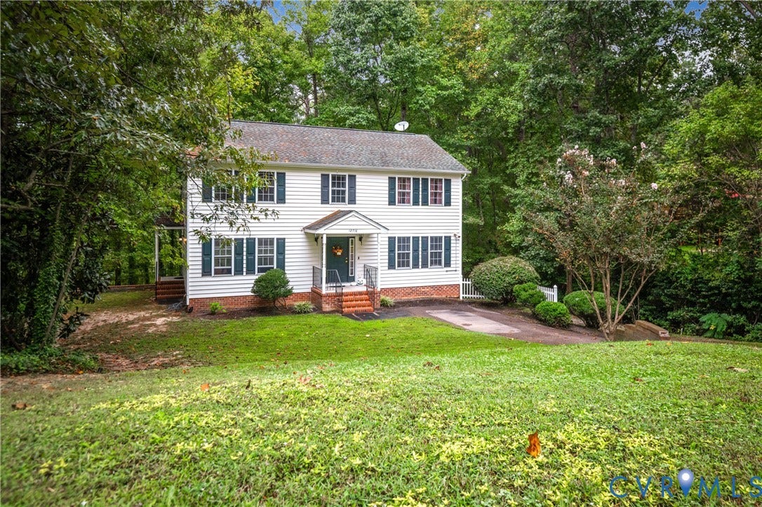 Two-story residence with white siding, dark green window shutters, and a covered front entry