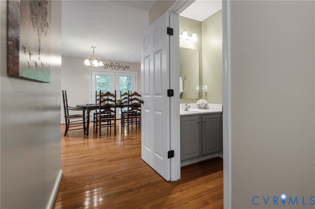 Hardwood flooring, vaulted ceiling, French doors, and a vanity with a rectangular sink and a two-door cabinet