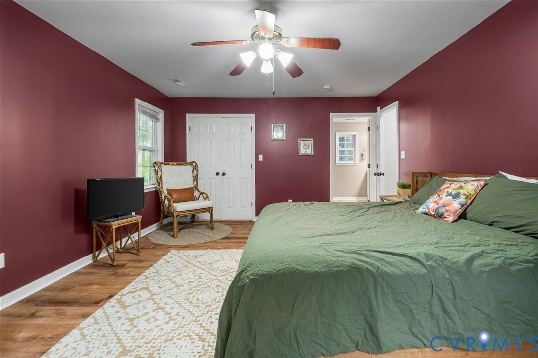 Wood-finish flooring with white trim, a ceiling fan with light fixture, and a white paneled door