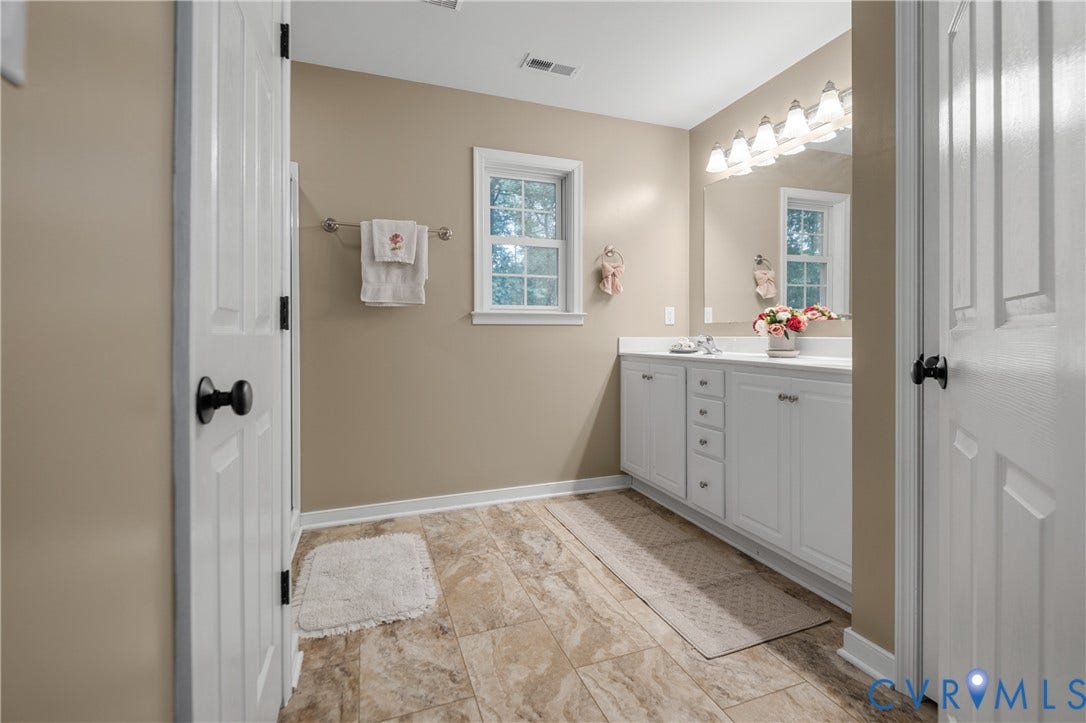 Bathroom featuring a single window, a dual-cabinet vanity with a countertop, an overhead vanity light fixture, and tile flooring