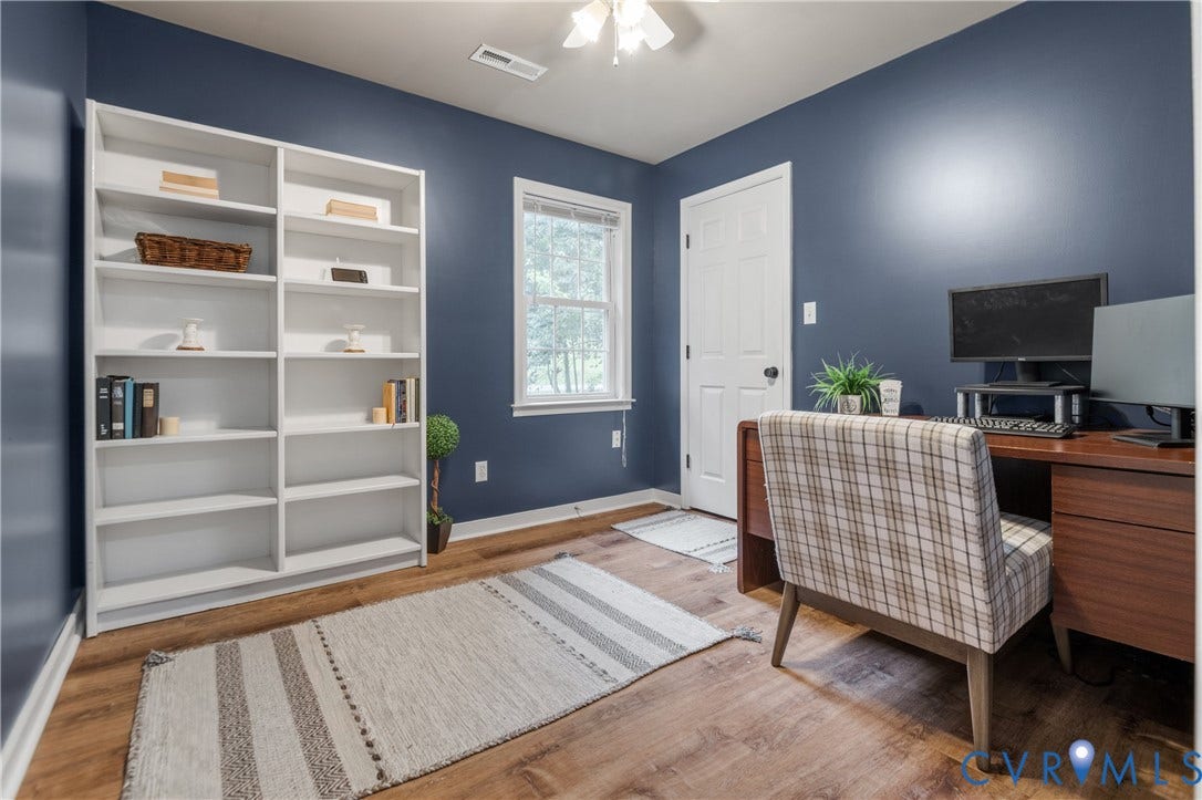 Wood-finish flooring, built-in shelving, white trim, ceiling fan, and a paneled door