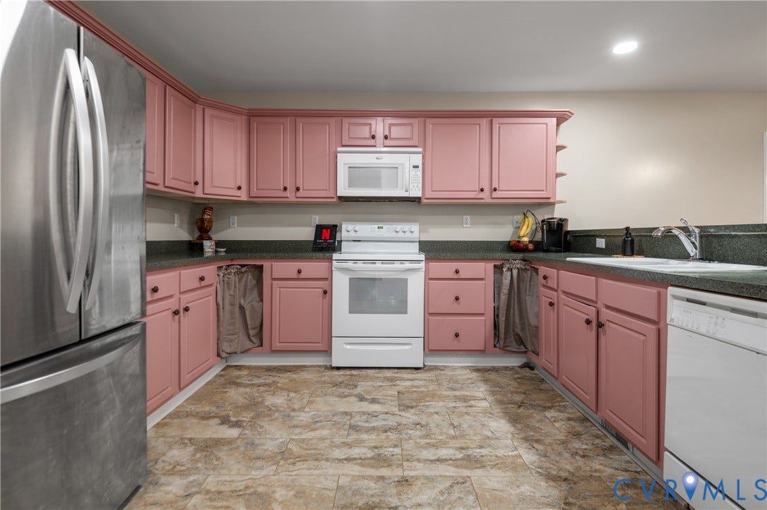 Kitchen featuring pink cabinetry, dark countertops, white range, stainless steel refrigerator, and tile-look flooring