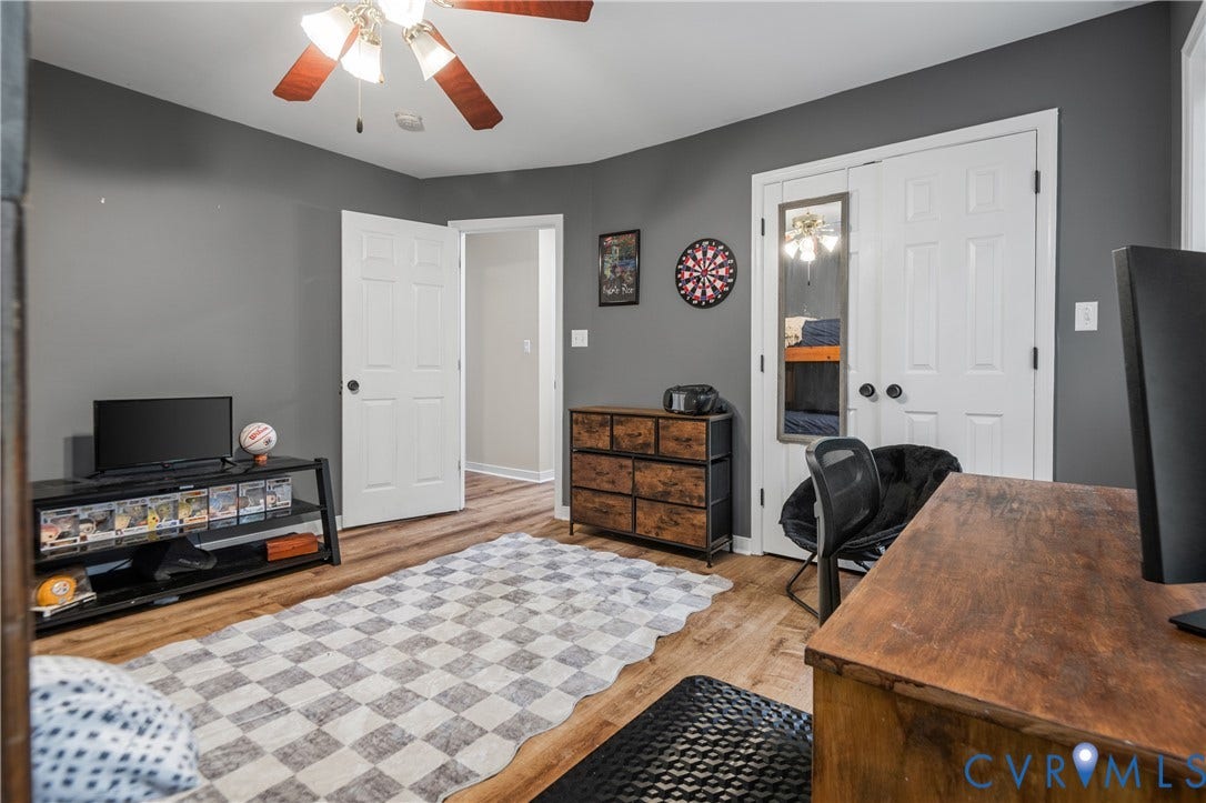 Wood-finish flooring, white paneled doors, ceiling fan with integrated lighting, and a double-door closet
