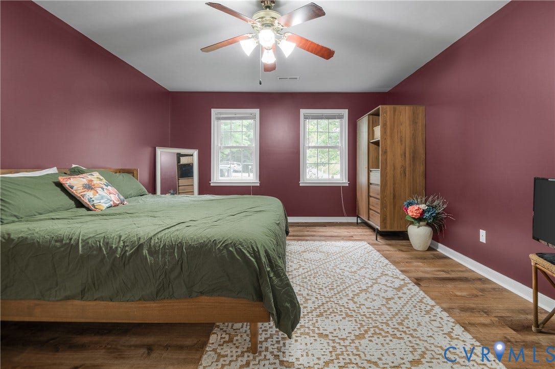 Wood-finish flooring with white trim and a ceiling fan