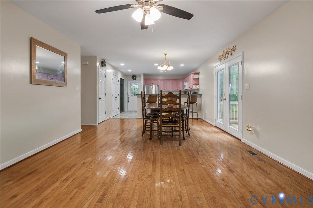 Wood-finish flooring throughout, integrated ceiling fan with lighting, double French doors, recessed lighting, and a chandelier in the background