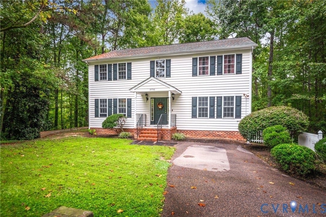 Two-story colonial-style residence with white siding, dark shutters, and a covered front entry