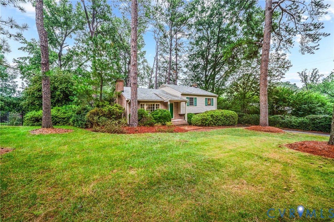 7548 Piney Branch Road, Stratford Hills, Richmond, VA 23225 Brick exterior residence with a partial white facade, green window shutters, a front porch with a green door, and mature trees