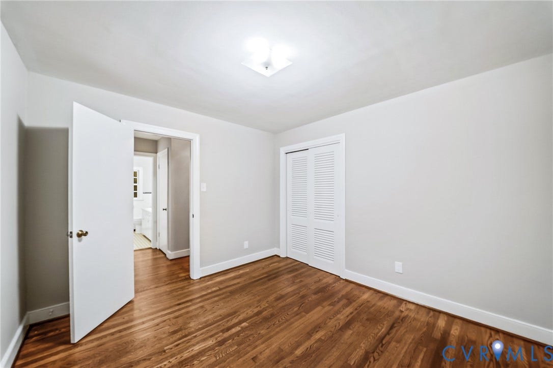 7548 Piney Branch Road, Stratford Hills, Richmond, VA 23225 Wood-finish flooring, white walls, white trim, louvered bi-fold closet doors, and an overhead flush-mount light fixture