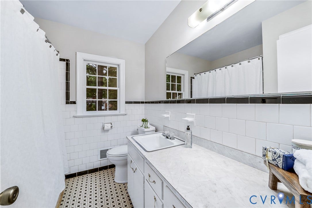 7548 Piney Branch Road, Stratford Hills, Richmond, VA 23225 Bathroom featuring subway tile walls with black trim, a large vanity with an integrated sink, a window with muntins, and patterned floor tiles