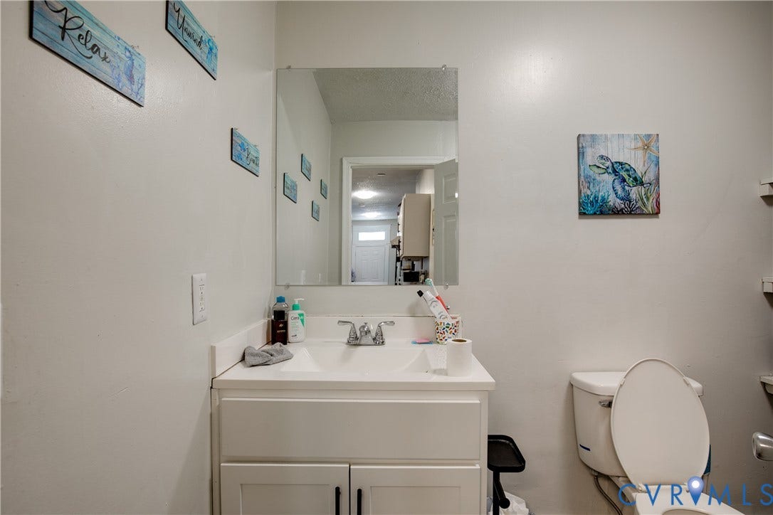3314 3rd Avenue, Northside, Richmond, VA 23222 Bathroom featuring a white vanity with integrated sink, chrome faucet, wall-mounted mirror, and a white toilet