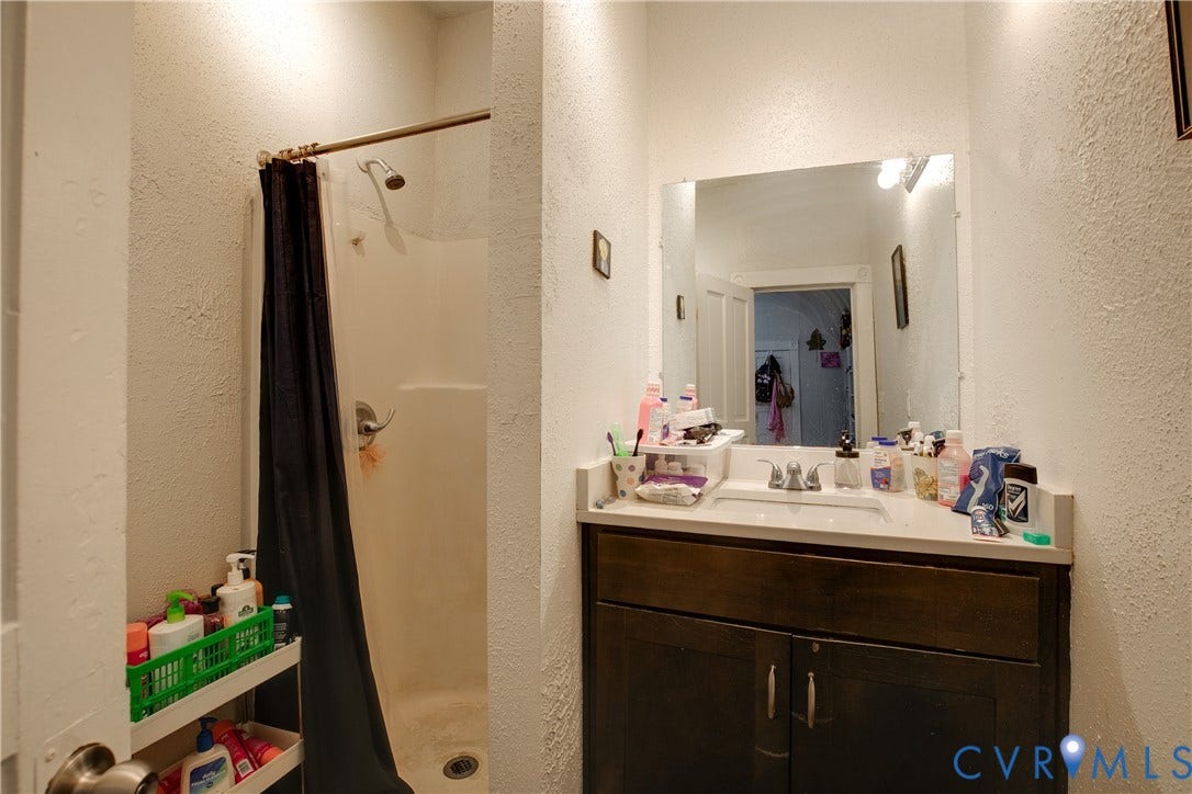 3314 3rd Avenue, Northside, Richmond, VA 23222 Vanity with an integrated sink, a dark wood-finish cabinet, and a wall-mounted mirror with overhead lighting