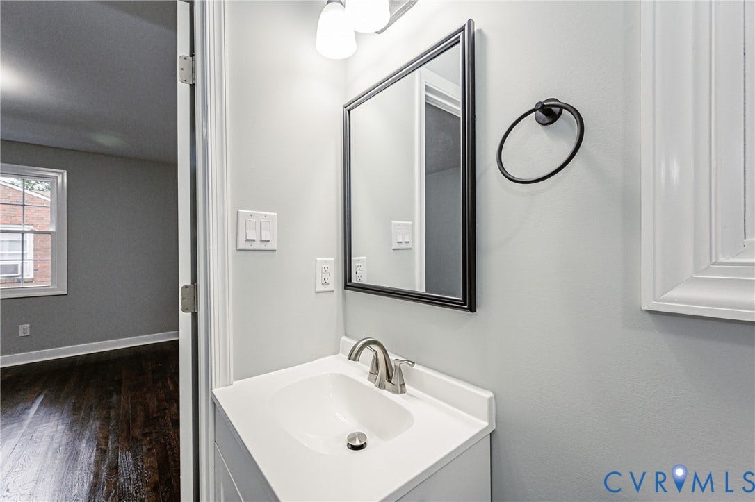1608 Bryan Street, Richmond, VA 23223 Bathroom vanity with a white countertop and integrated sink, framed mirror, and wall-mounted light fixture