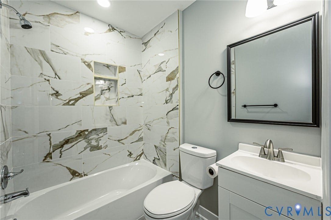 1608 Bryan Street, Richmond, VA 23223 Bathtub featuring a tiled shower surround with a built-in niche, modern vanity with an integrated sink, and wall-mounted mirror