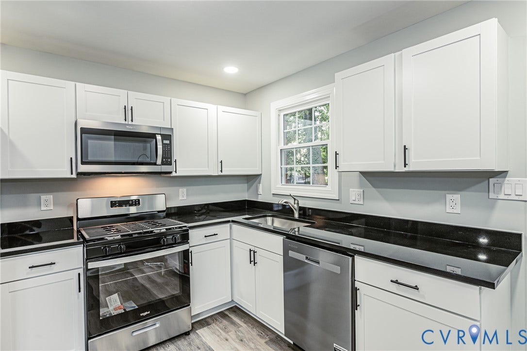 1608 Bryan Street, Richmond, VA 23223 Kitchen featuring stainless steel appliances, solid surface countertops, white shaker cabinetry with matte black hardware, and wood-finish flooring