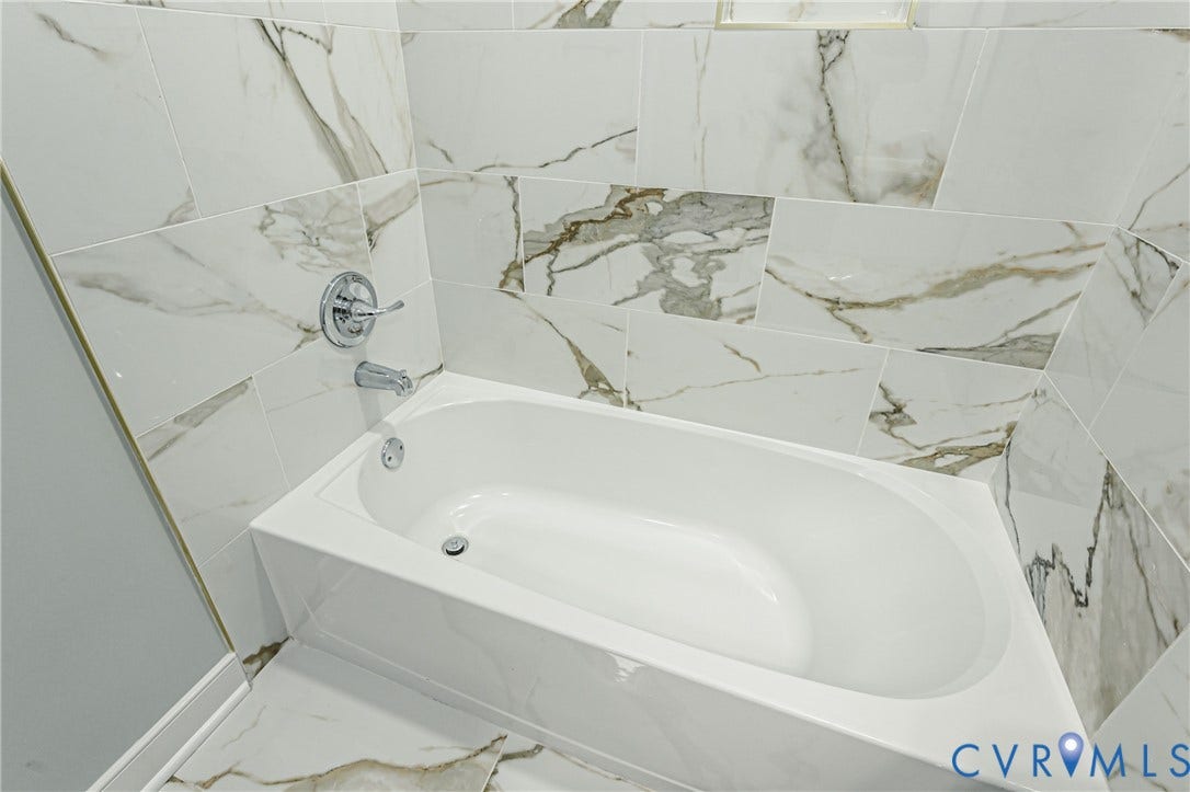 1608 Bryan Street, Richmond, VA 23223 White bathtub with chrome fixtures, surrounded by white and gray patterned tile
