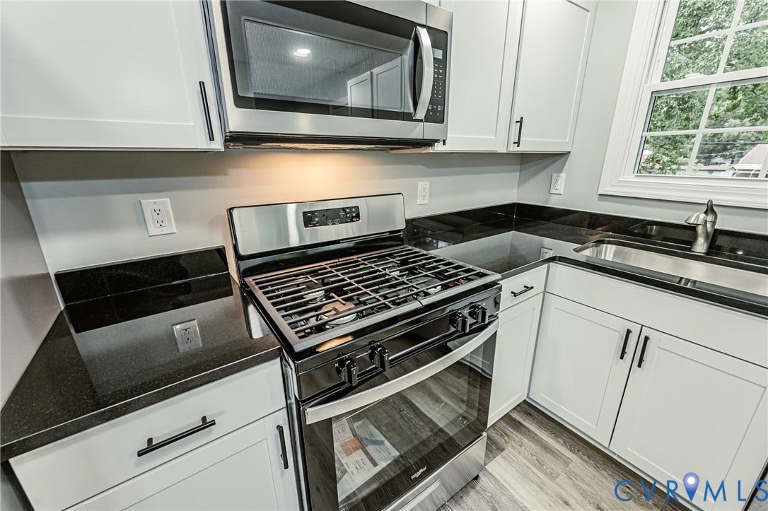 1608 Bryan Street, Richmond, VA 23223 Kitchen featuring white cabinetry, dark countertops, stainless steel appliances, and wood-finish flooring