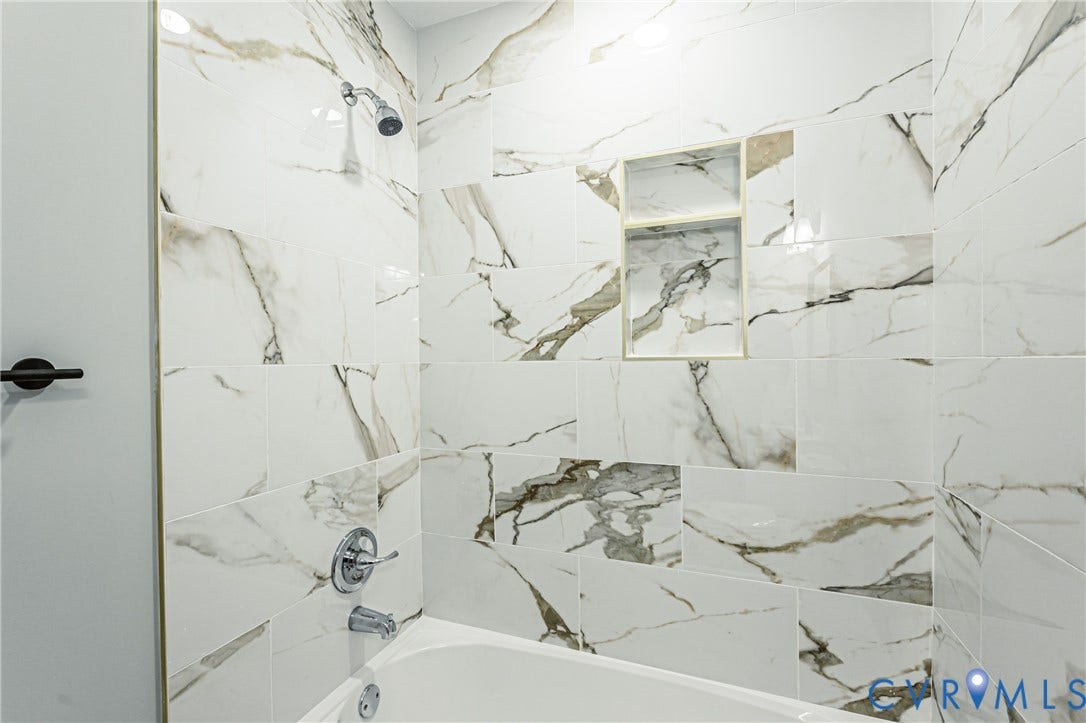 1608 Bryan Street, Richmond, VA 23223 Bathtub and shower combination featuring a built-in shower niche, chrome showerhead, and tile surround with veining