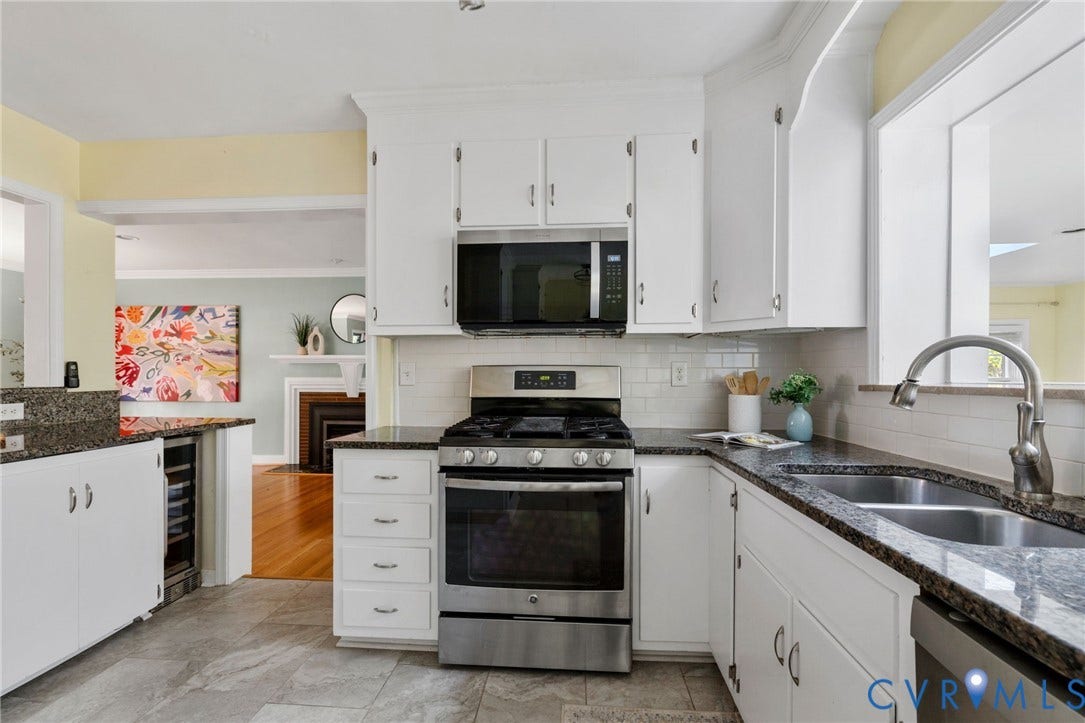 White cabinetry, dark stone countertops, subway tile backsplash, stainless steel appliances, and a dual-basin sink