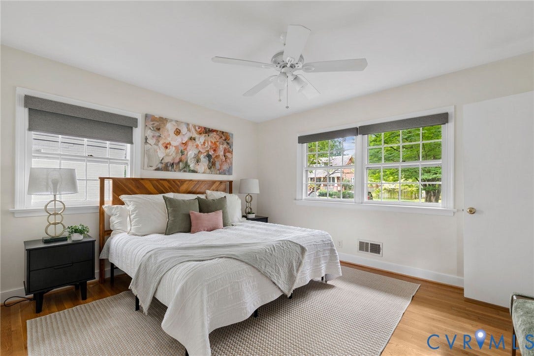 Hardwood flooring, multiple windows with white trim, ceiling fan, and white walls