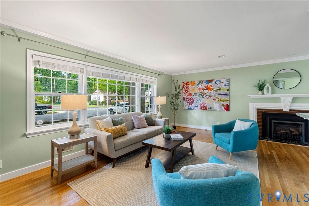 Hardwood flooring, crown molding, white trim, multiple windows with grid panes, and a fireplace with a detailed mantel