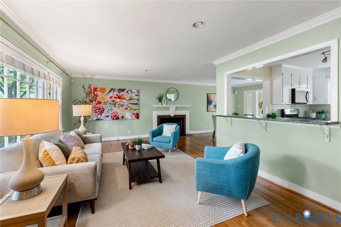 Hardwood flooring, crown molding, white fireplace mantel, built-in kitchen pass-through, and white cabinetry