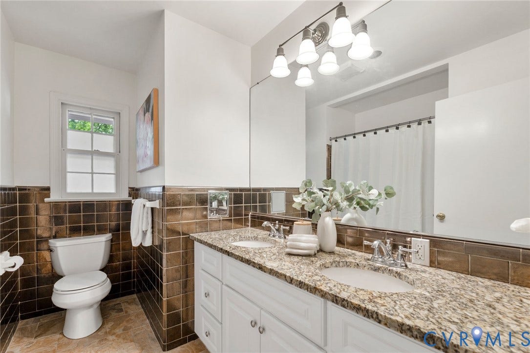 Dual vanity with granite countertop, white cabinetry, and undermount sinks