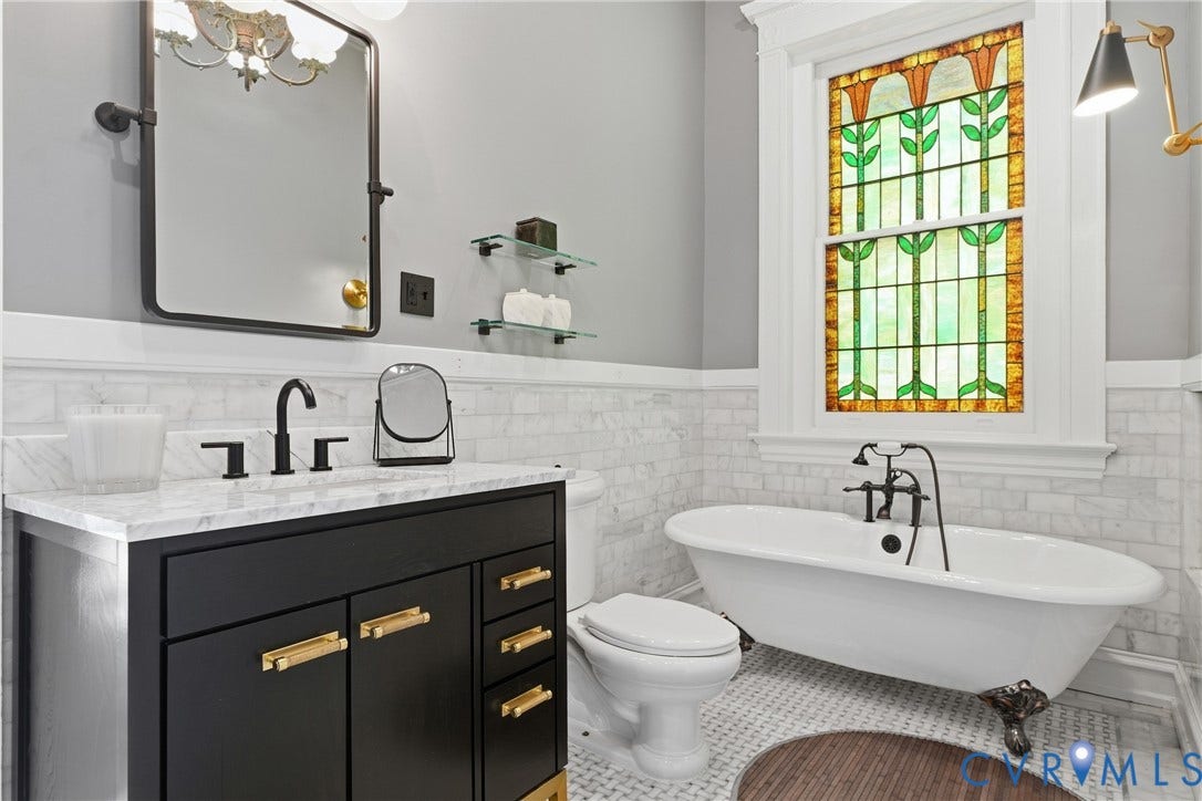 1848 W Grace Street, Historic W. Grace Street, Richmond, VA 23220 Stained glass window, freestanding clawfoot tub, dark wood-finish vanity with gold-tone hardware, white marble countertop, and black fixtures