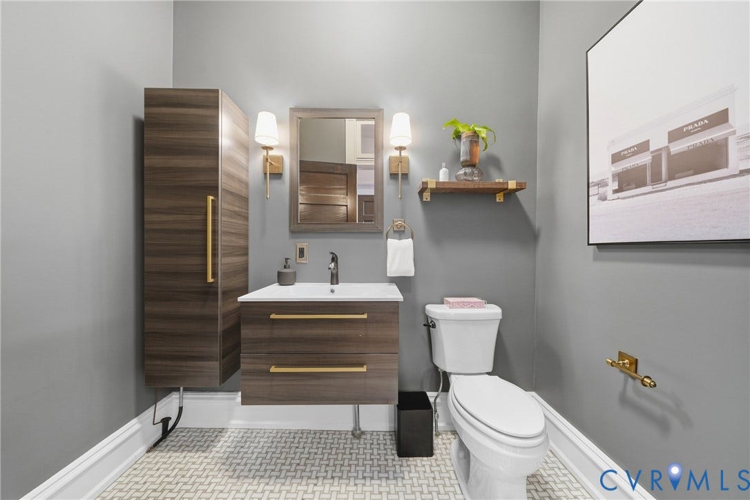 1848 W Grace Street, Historic W. Grace Street, Richmond, VA 23220 Powder room featuring mosaic tile flooring, floating wood-finish vanity, wall-mounted storage cabinet, and wall sconces