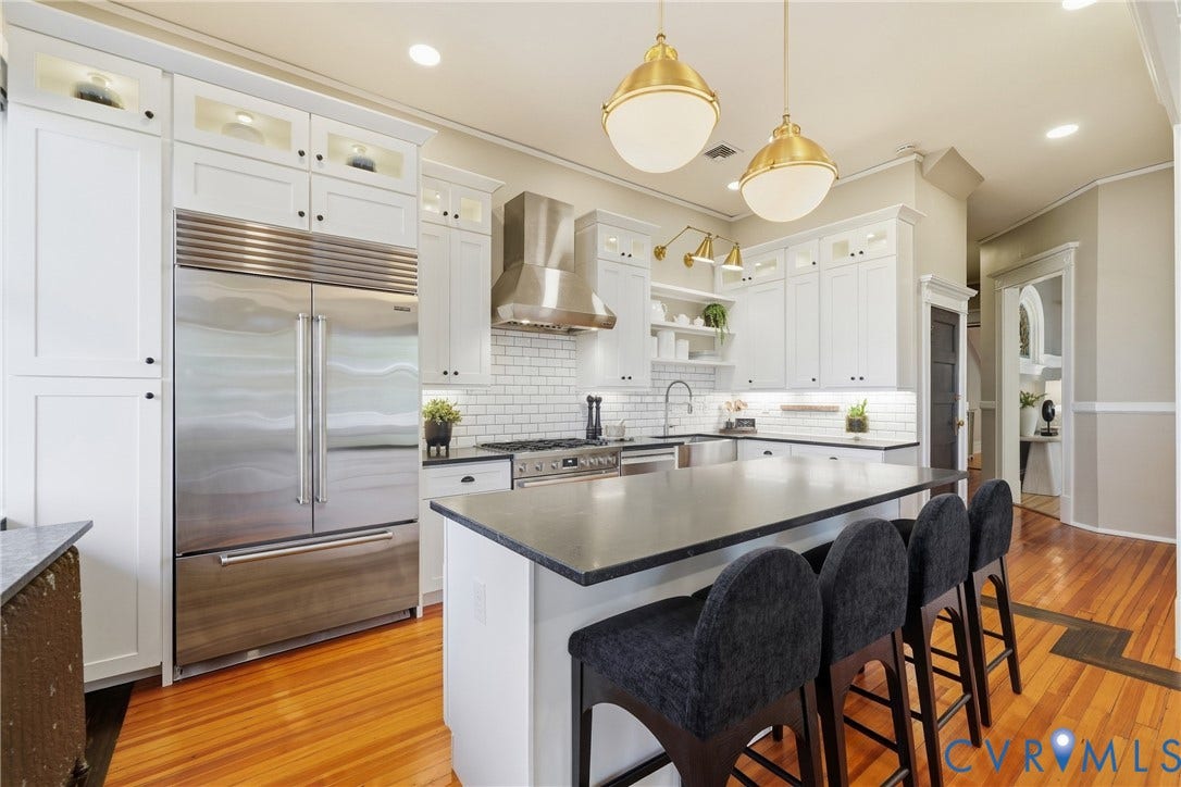 1848 W Grace Street, Historic W. Grace Street, Richmond, VA 23220 White shaker cabinetry, stainless steel appliances, central island with seating, subway tile backsplash, and wood flooring