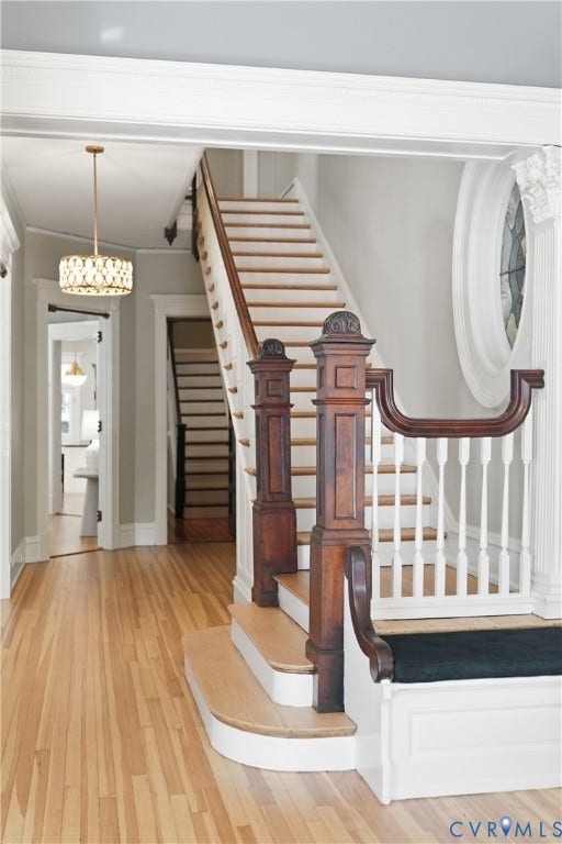 1848 W Grace Street, Historic W. Grace Street, Richmond, VA 23220 Hardwood flooring throughout, a grand staircase with dark wood newel posts, white balusters, and a built-in bench, complemented by a decorative overhead light fixture