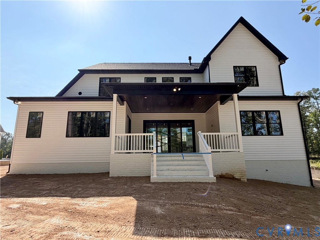Contemporary exterior with white siding and dark trim, featuring a covered patio, white railings, and multiple windows