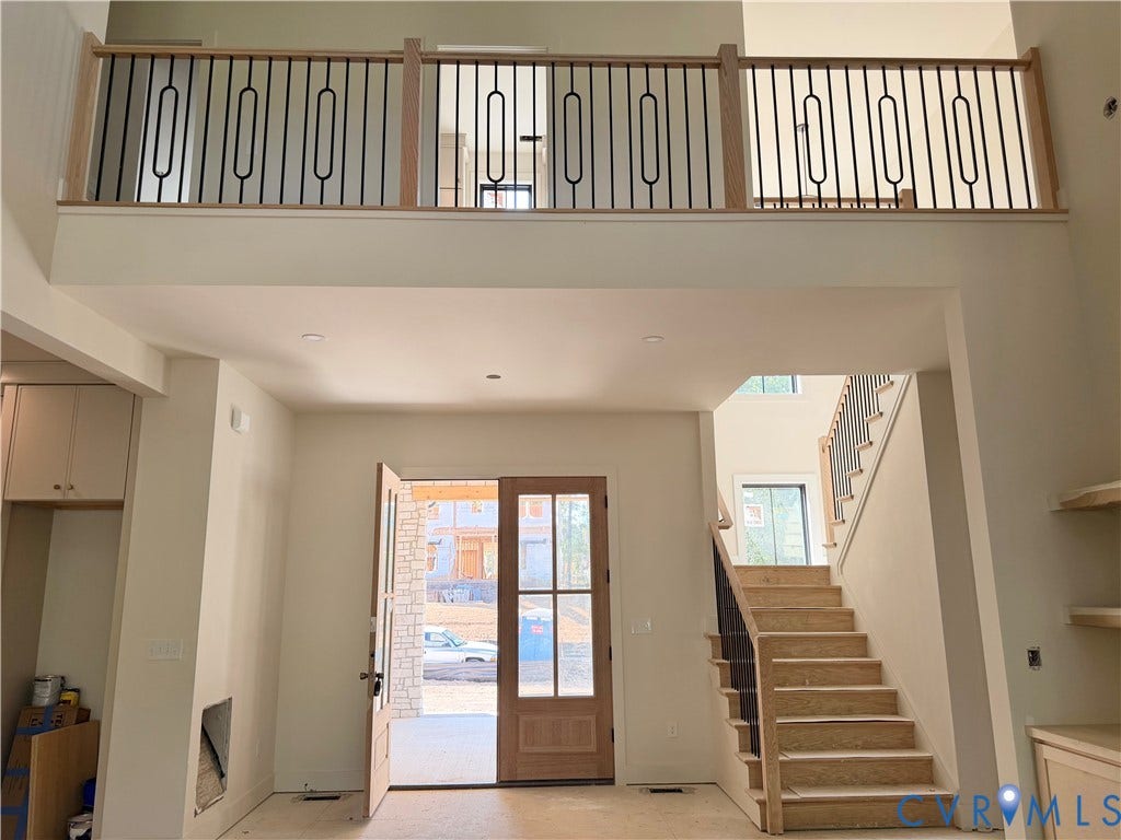 Two-story foyer with a natural wood staircase, wrought iron balusters, and recessed lighting