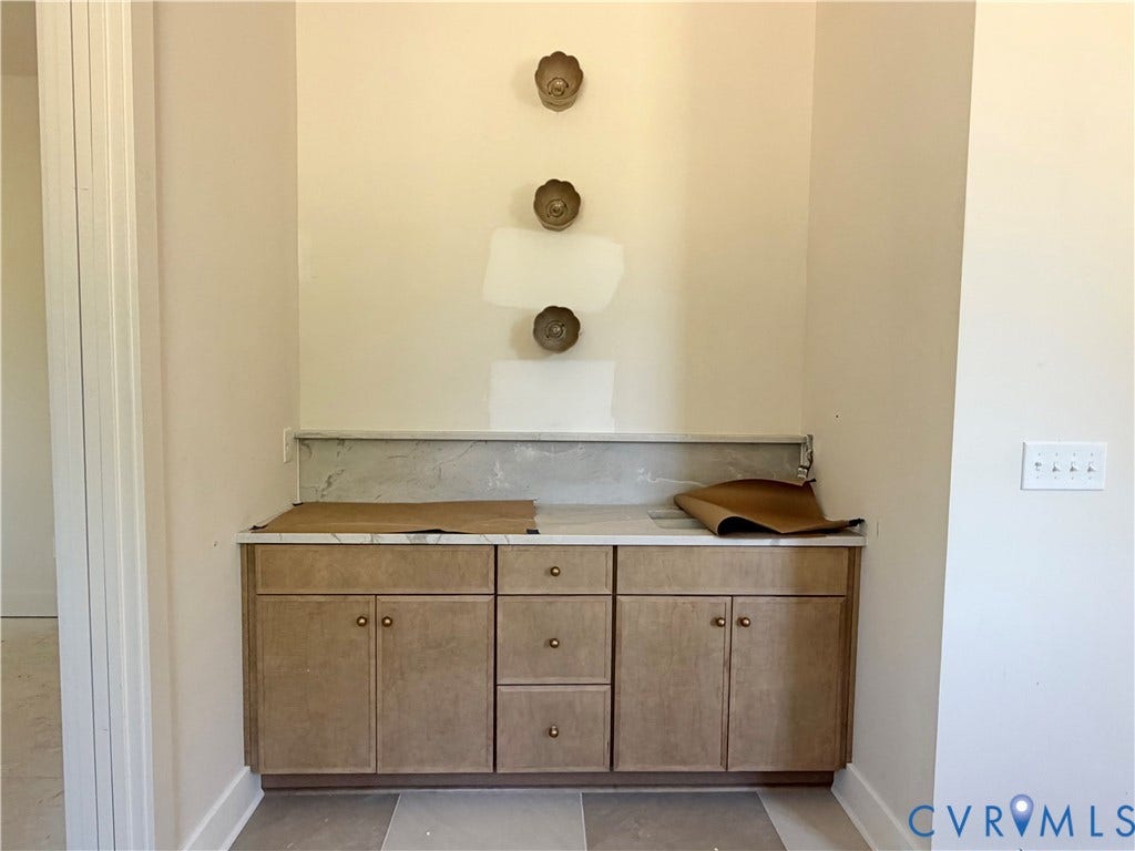 Built-in cabinetry with wood-finish doors and drawers, complemented by a stone-look countertop and backsplash