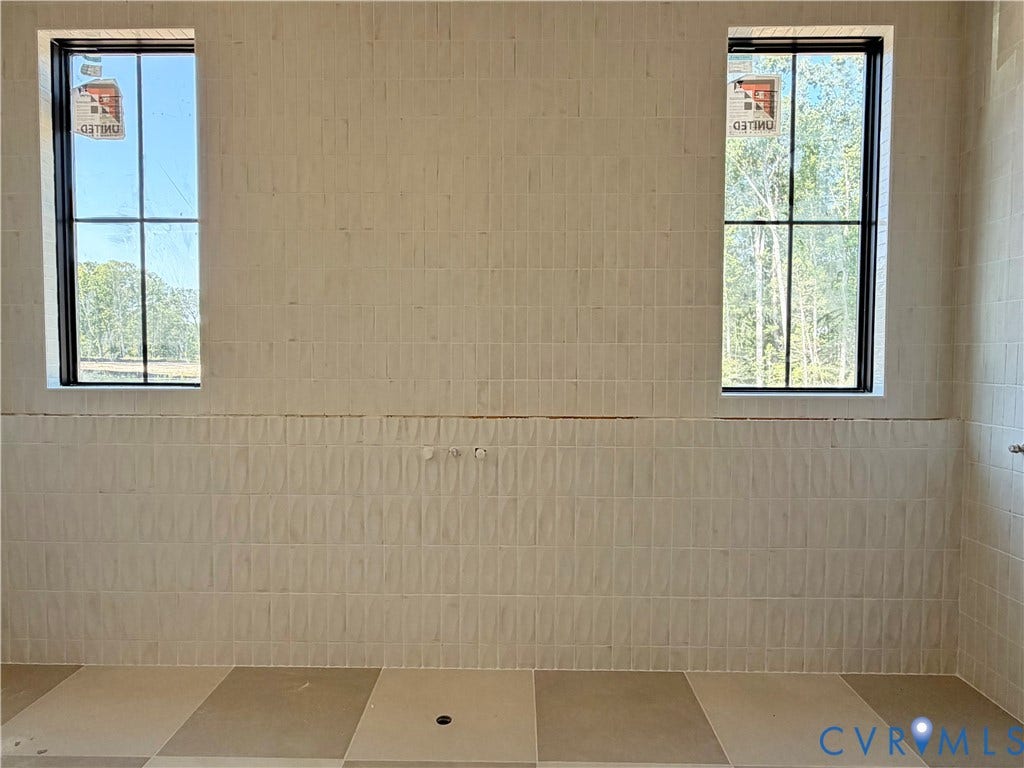 Floor-to-ceiling tile, two vertical windows with black frames, and a tiled floor