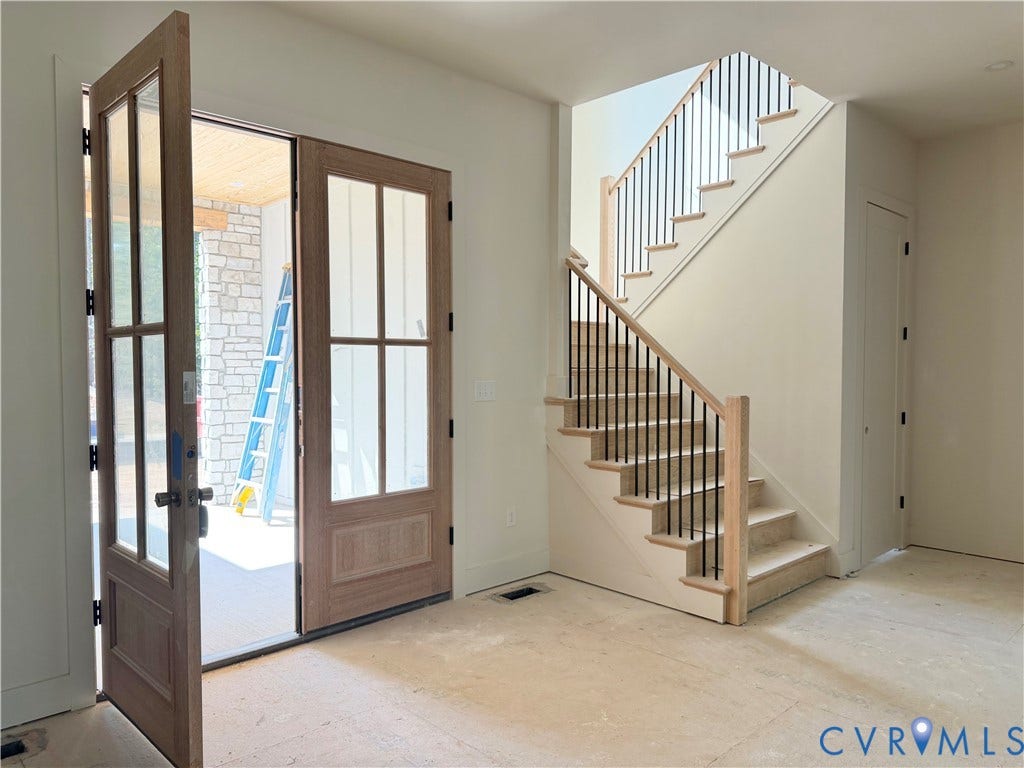 Double-entry doors with glass panels, light wood-finish staircase with black metal balusters, and a built-in closet with a white door
