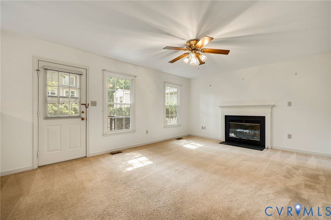 3005 Wiltonshire Drive, Richmond, VA 23233 Carpeted living space featuring a white mantel fireplace, two windows, and a ceiling fan with integrated lighting